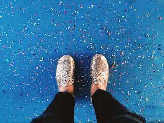 First person view of someone looking down at their shoes and confetti on the ground