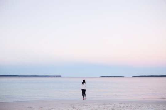 A woman stands at the water's edge of Hyam's Beach, Jervis Bay