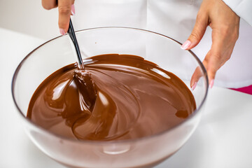 Closeup stirring mixing milk melted chocolate in glass bowl isolated on white background....