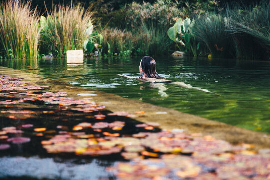 Young woman swimming in an eco pool at wellness spa for relaxation
