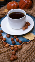 Autumn background with coffee, knitted scarf, pumpkin. Autumn coffee, dry leaves. Season October, November.