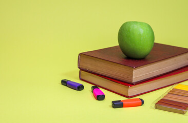 green apple and books
There is a green apple on two brown books, close-up side view of plasticine and three markers with space for text on the left.
