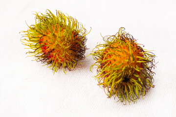two rambutans fresh and shaggy exotic fruit lies on a white background
