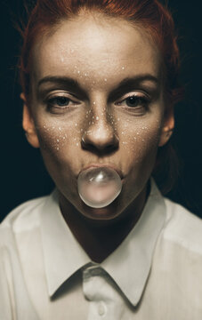 Fashionable/conceptual portrait of hip young ginger female with bubble gum.