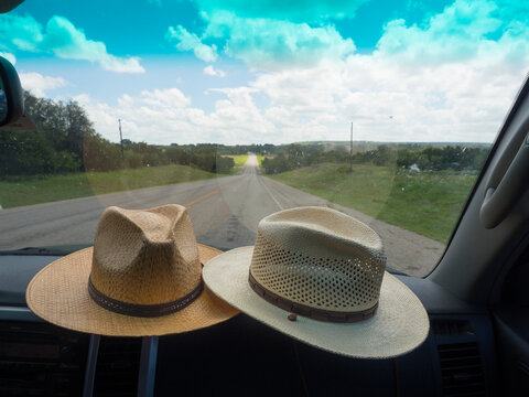 Cowboy hats on car dashboard while driving on rural country roads