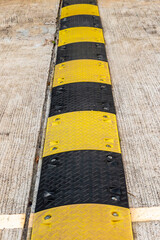 speed bump located, black and yellow vertical strip pedestrian safety close up