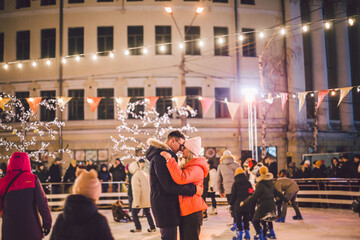 Beautiful couple have fun in ice arena. active date ice skating on ice arena in evening city square in winter Christmas Eve. St. Valentine's Day at the city ice rink. New Year's holidays in city Kiev