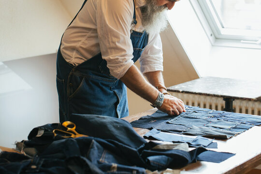 Cool Senior Male Tailor Creating Denim Patchwork Fabric at Home