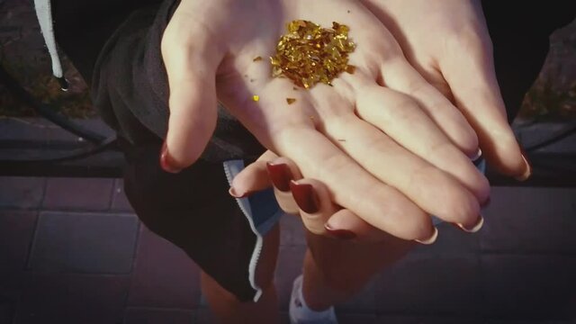 A girl is blowig out golden particles away from her palm slow motion shot