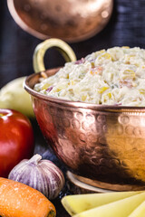 mayonnaise served in a rustic copper pot, with vegetables such as tomatoes, carrots, corn, eggs and peas. Typical Brazilian culture food