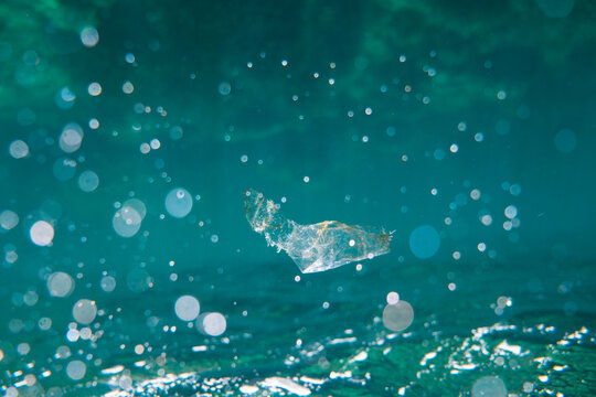 Piece of plastic waste floating in open blue sea