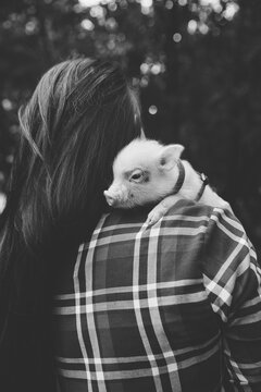 Black-haired woman carrying piglet on shoulder