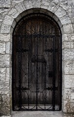 Old, vintage, wooden castle door, towers with metal bars.