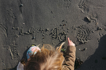 Little caucasian girl writing in sand