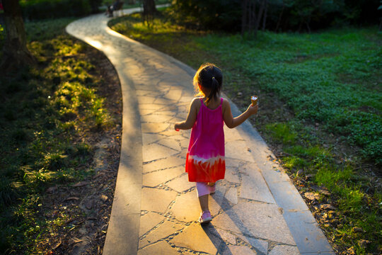 little girl walking in tha park with iceream in hand