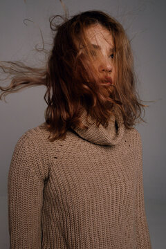 Woman with windy hair in brown sweater