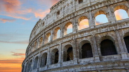 Obraz premium The Colosseum in Rome, Italy in the early evening with a colorful sky in the background.