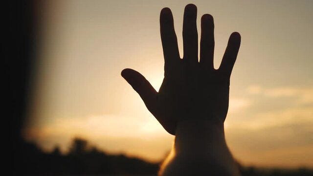 girl stretches out her hand in the sun. faith in god dream a religion concept. hand in the sun close-up silhouette dream of sunlight happiness