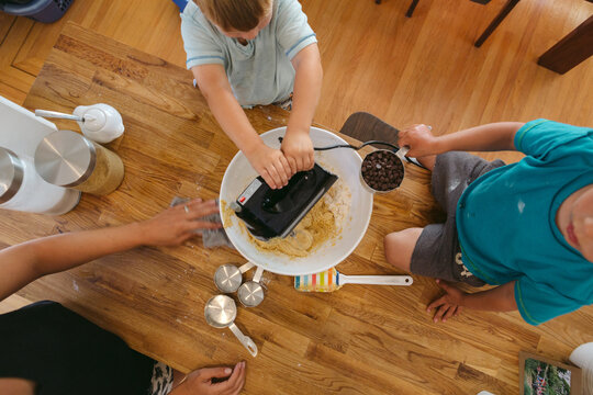 3 year old caucasian boys baking together at kitchen bar with yo