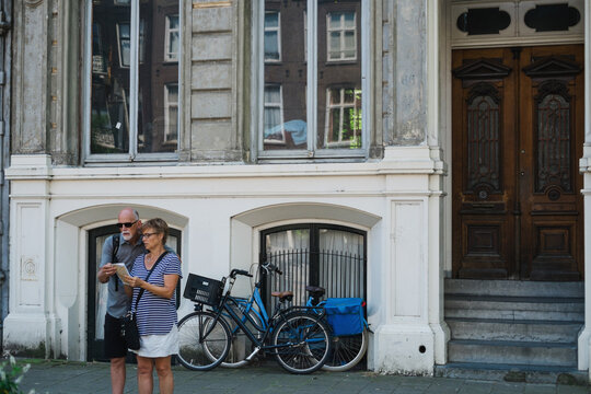 Middle age couple looking confused at map on city street