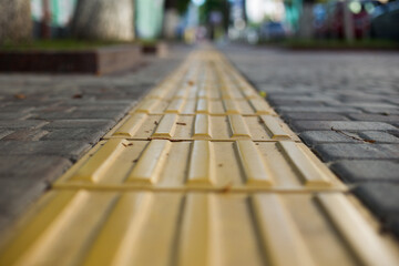 Yellow tactile tiles for the blind and visually impaired on the sidewalk in the city on the street