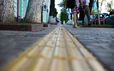 Yellow tactile tiles for the blind and visually impaired on the sidewalk in the city on the street