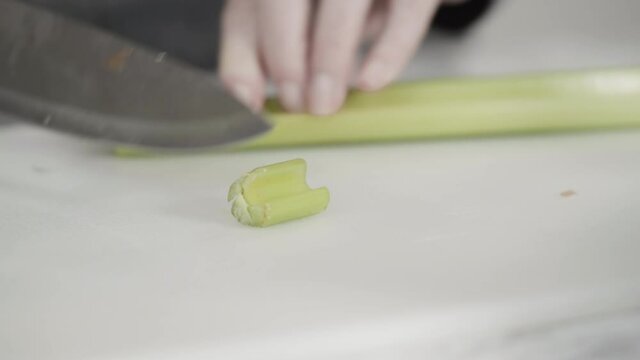 Curring vegetables on a white cutting board to cook vegetarian white bean soup.
