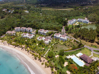 Obraz premium Aerial drone view of tropical beach residence (condo) at the paradise beach with the pool, palm trees and blue water of Atlantic Ocean, Las Terrenas, Samana, Dominican Republic