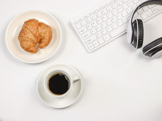 flat lay of coffee cup ,croissant ,computer keyboard and headphones on white background with copy space. working time concept.