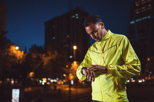 Handsome athlete in yellow checking time - Powered by Adobe