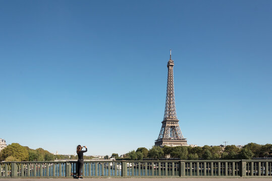 A young woman taking photos of Eiffel Tower with an phone in Paris
