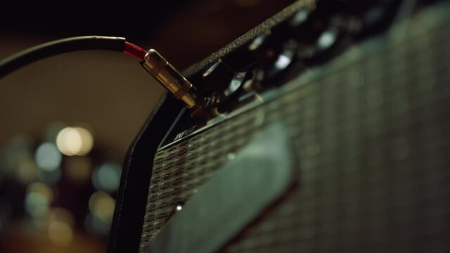 Sound engineer connecting amplifier in concert hall. Man hand sticking plug.