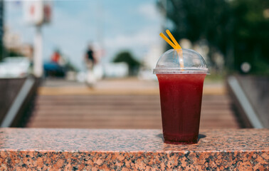 Red raspberry drink in a plastic glass with a straw