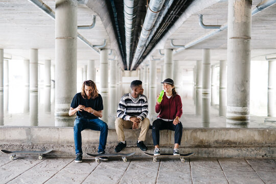 Three skateboarders sitting on a concrete border and relaxing.