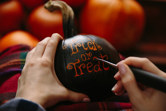 Girl carving with knife words on pumpkin
