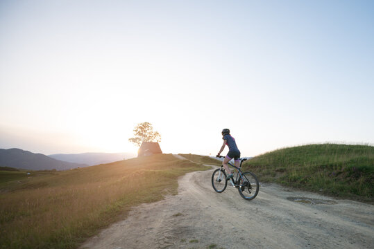 Female riding mountain bike along a mountain trail during susnet
