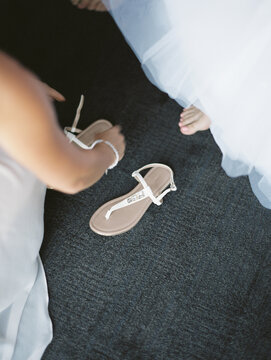 bridesmaid helping the bride to put her shoes on