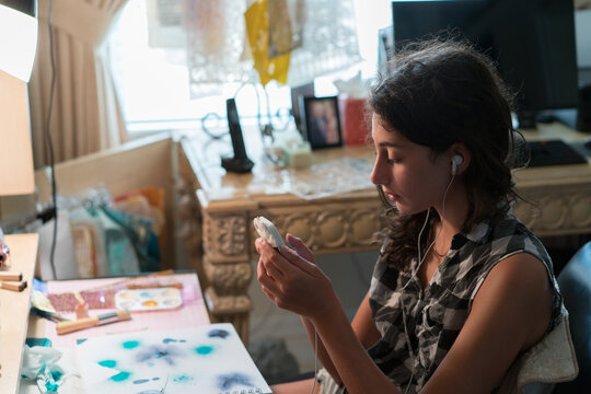 Teenager with mobile phone in hand and earplugs in ear