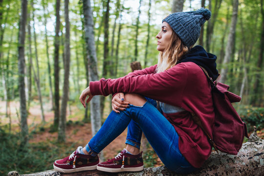Portrait of woman sitting on a log, in the middle of the forest
