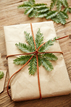 Gift wrapped in brown paper with pine branches attached