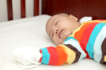 asian baby sleeping on the baby cot