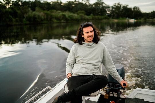 Young Man Steering a Small Boat on River