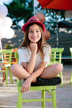 Young girl with red hat sitting on chair and smiling