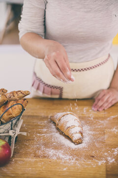Young woman's hands powdering sugar on croasant