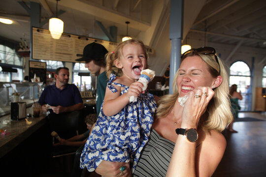 Mother Laughing While Toddler Licks Ice Cream Cone