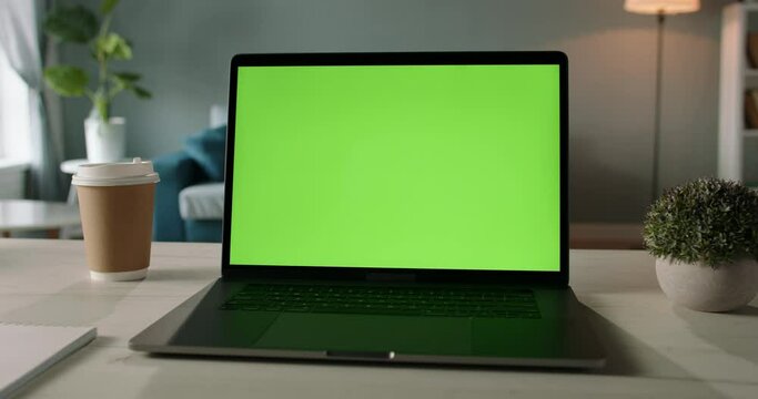 The table of distant worker at home. Modern laptop computer with chroma key green screen. Remote work, distance learning, technology concept close up 4k video template