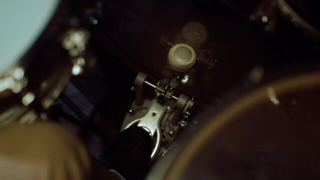 Drummer beating rhythm in studio. Man leg pressing drum pedal indoor.