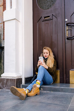 Beautiful woman using phone on doorstep