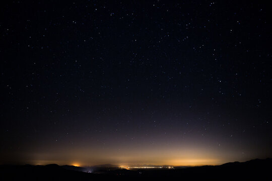 Small Desert Town Glowing at Night Against Starry Sky