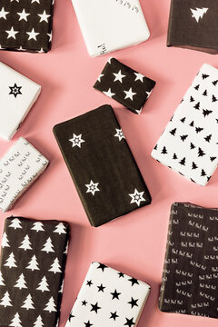 Christmas presents wrapped in self-made black and white paper on pink background